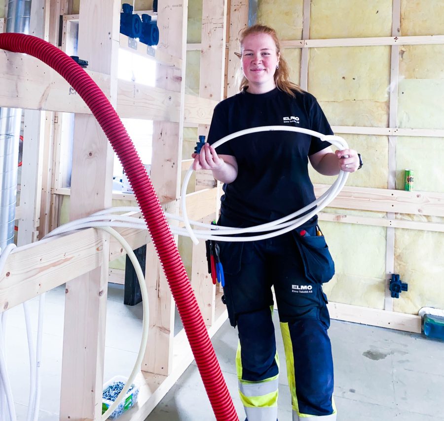 Ung kvinnelig elektriker på jobb i byggkonstruksjon.